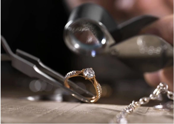 Quality inspector examining a finished jewellery piece with loupe
